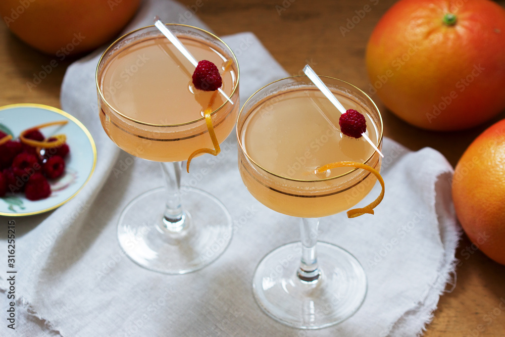 Champagne cocktail with grapefruit juice, garnished with zest and raspberries. Rustic style.