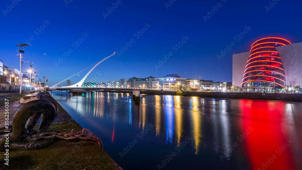 Blue hour at Dublin docks, Samuel Beckett bridge and convention centre. Illuminated embankment and blurred water. long exposure photography, Ireland