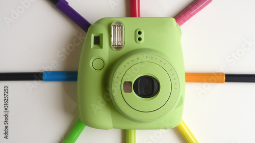 Green Instant Camera with Multicolored Brush Pens on a White Background