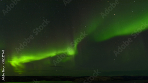 Aurora borealis over the hills. At night in the sky in the north. © Moroshka