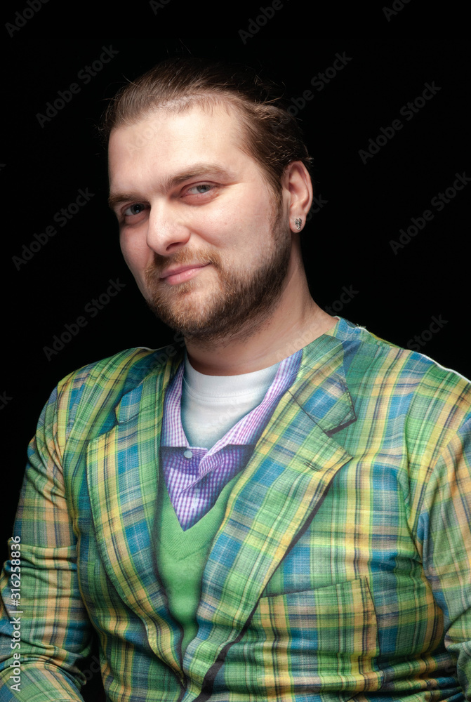 Obraz premium portrait of handsome positive bearded man with stylish and earring in green elegance blazer looking at camera isolated on black