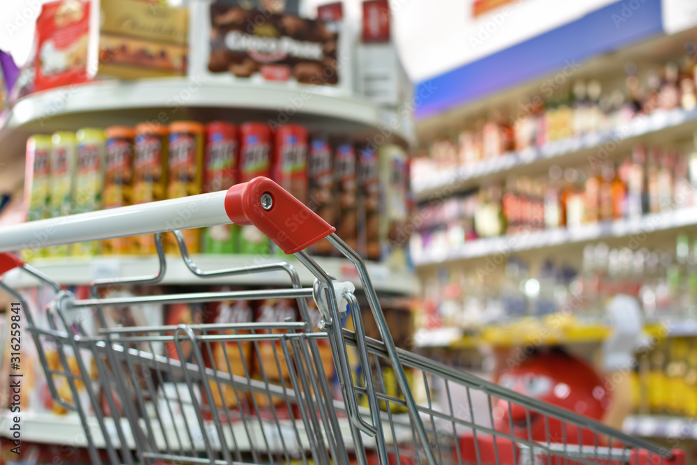 Supermarket store blurred background with close up shopping cart