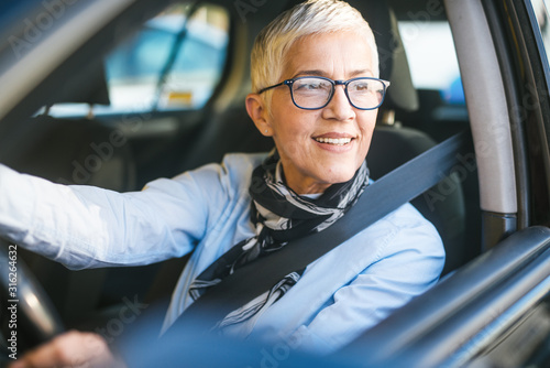 Happy and smiling senior woman in black car