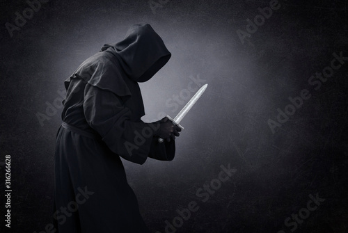 Hooded man with dagger in the dark