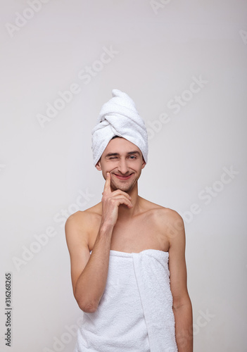 A young white man after a shower winks and smiles.