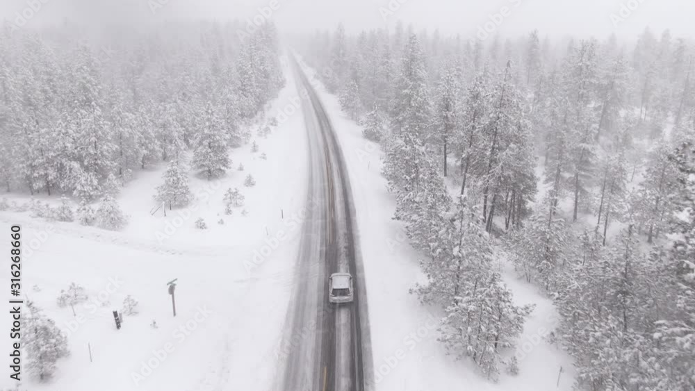 DRONE: Commuter on their way back home from work drives through a severe snowstorm covering the forests of Washington with fresh powder snow. Tourists on road trip drive through a raging blizzard. DRONE: Commuter on their way back home from work drives through a severe snowstorm covering the forests of Washington with fresh powder snow. Tourists on road trip drive through a raging blizzard.