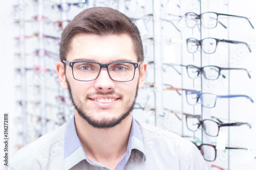 healthcare, people, vision and vision concept. men smiling trying on glasses in the store.
