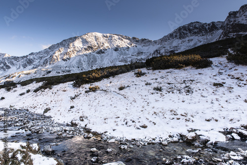 Potok górski zimą. Panorama gór polskich. Widok na pokryte śniegiem wysokie góry. Tatry. Polska. Tatrzański Park Narodowy w słoneczny dzień.  photo