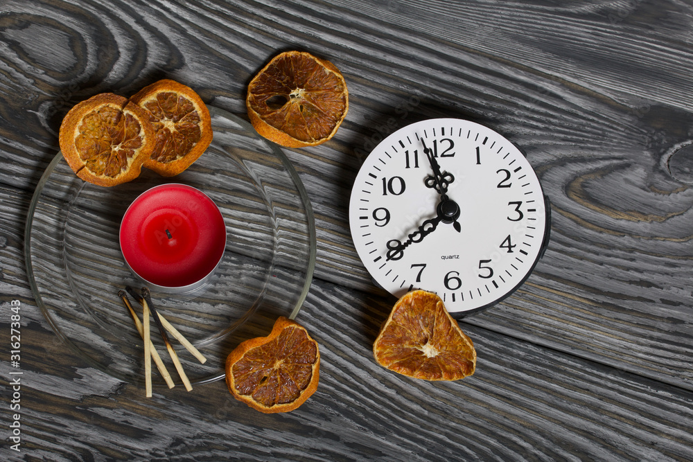 Candle on brushed boards. Near the clock, matches and dried oranges. Candle on brushed boards. Near the clock, matches and dried oranges.
