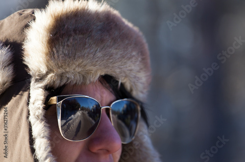 beautiful girl with sunglasses and cap, photographed in the winter on the mountain