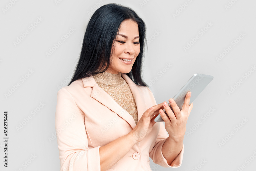 Freestyle. Asian businesswoman standing isolated on white with digital tablet browsing internet cheerful Freestyle. Asian businesswoman standing isolated on white with digital tablet browsing internet cheerful