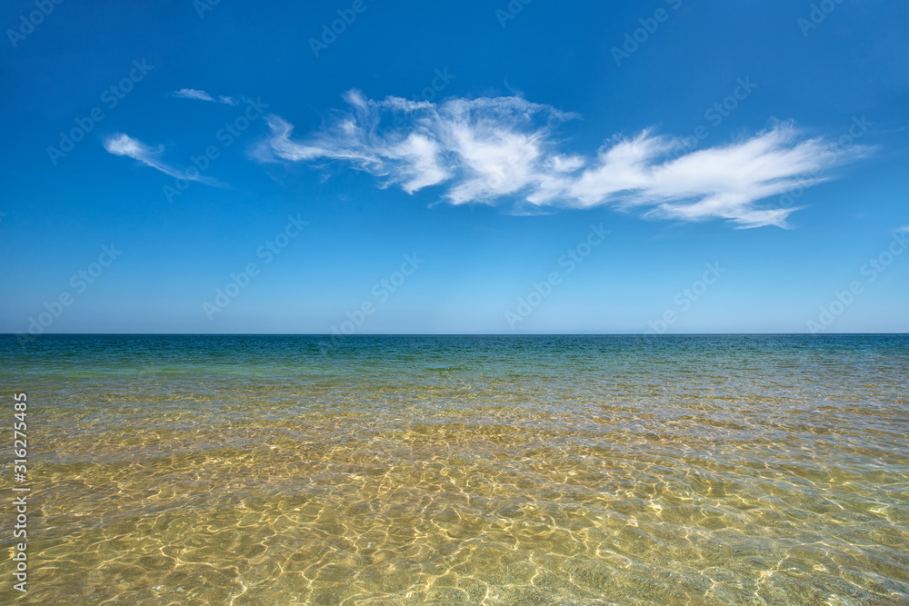 Transparent sea with a white cloud in the background