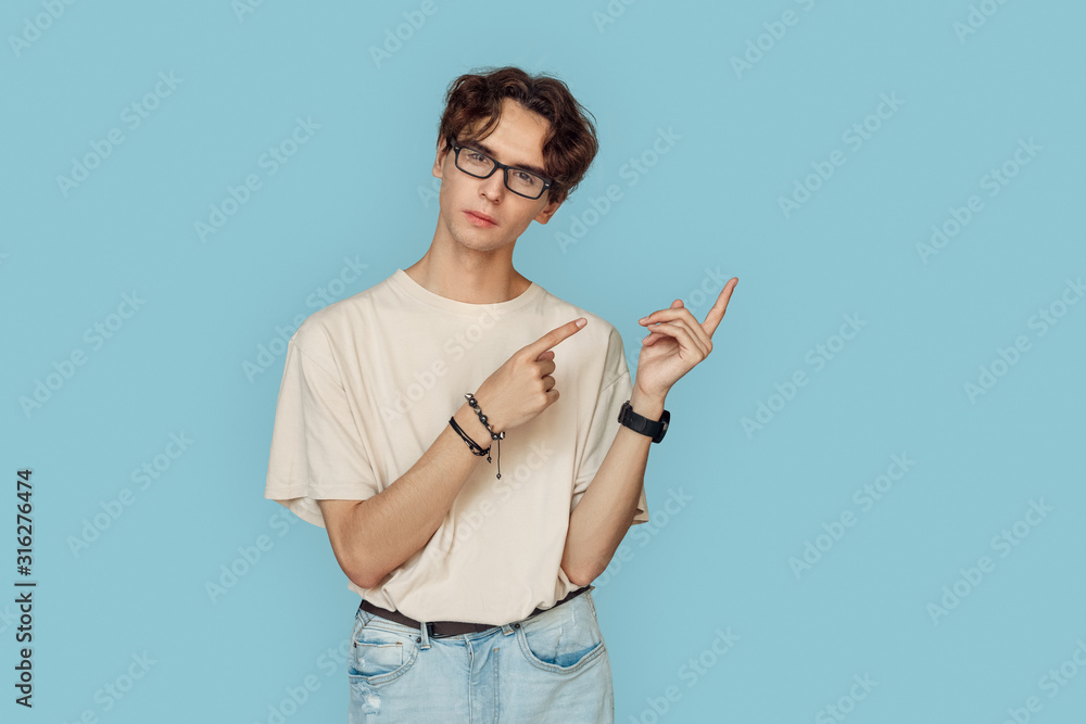 Freestyle. Man in glasses standing isolated on gray pointing aside at copy space pensive Freestyle. Man in glasses standing isolated on gray pointing aside at copy space pensive
