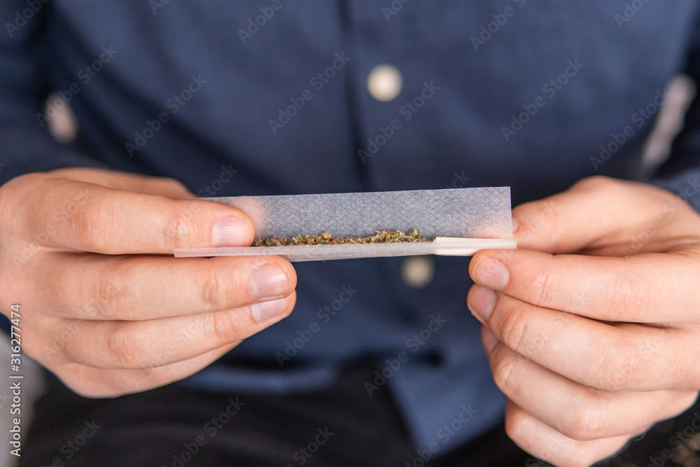 Close up of addict lighting up marijuana joint with lighter. Man ...