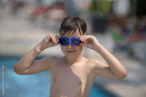 Portrait of smiling Caucasian boy spending time in pool at resort. He is enjoying his summer holidays.
