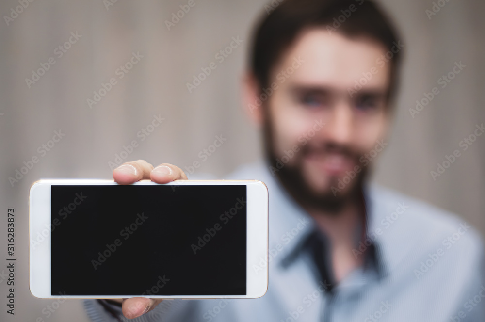 Business man holds and shows mobile phone. Bearded man in suit showing smart phone with blank screen. Business, communication, internet, technology concept Business man holds and shows mobile phone. Bearded man in suit showing smart phone with blank screen. Business, communication, internet, technology concept
