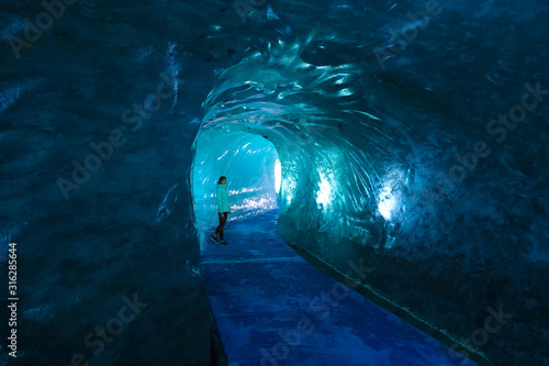 Female traveler walks along a path running through a breathtaking glacier. photo