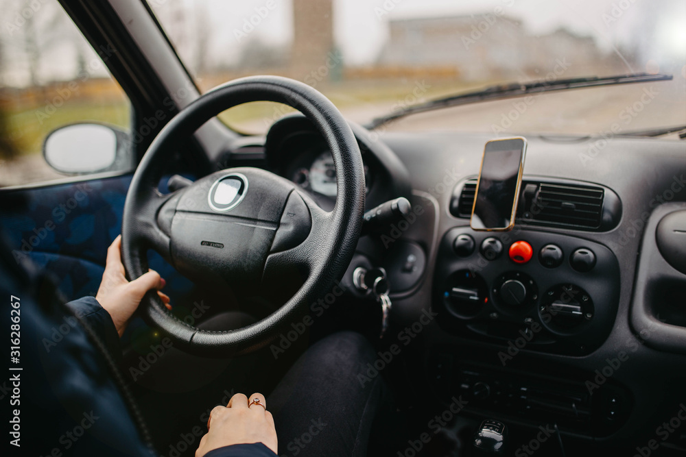 female hand holds the steering wheel of a car. Woman driver concept.