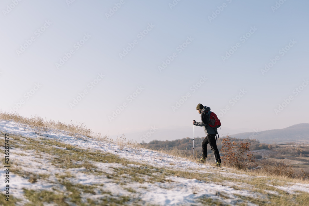 Obraz premium Side view of hiker walking on hill during winter