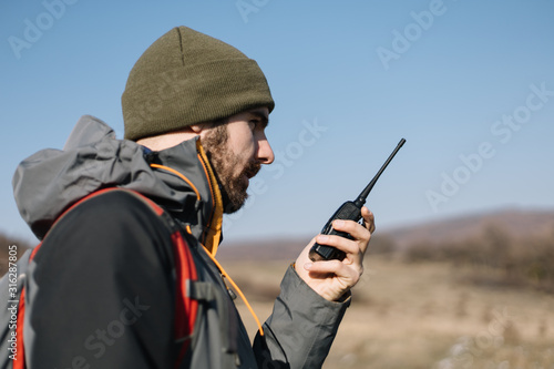 Tourist man speaking on mountain walkie talkie