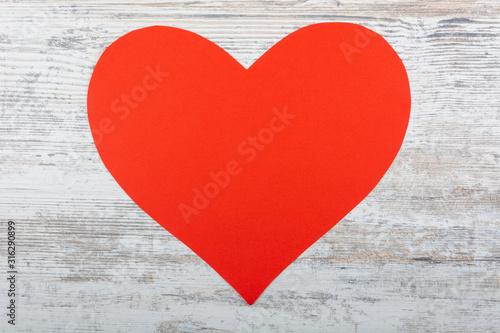 A large paper red heart for inscription lies on a white wooden background. Valentine's day, wedding, declaration of love. Space for text, top view, flat lay, copy space.