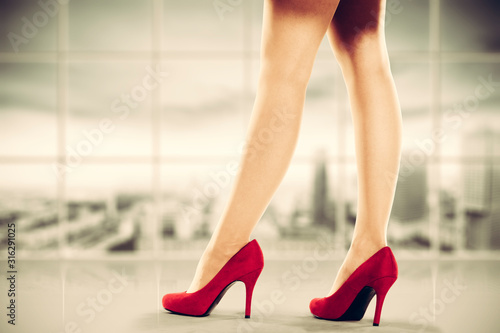 Woman legs with red heels and office interior 