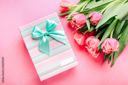 Gift box and bouquet of beautiful tulips on pink background, close up