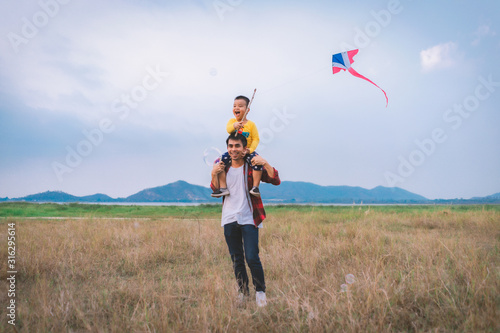 Happy family Father and child with a kite and bubble amid of nature in the summer on wide meadow..