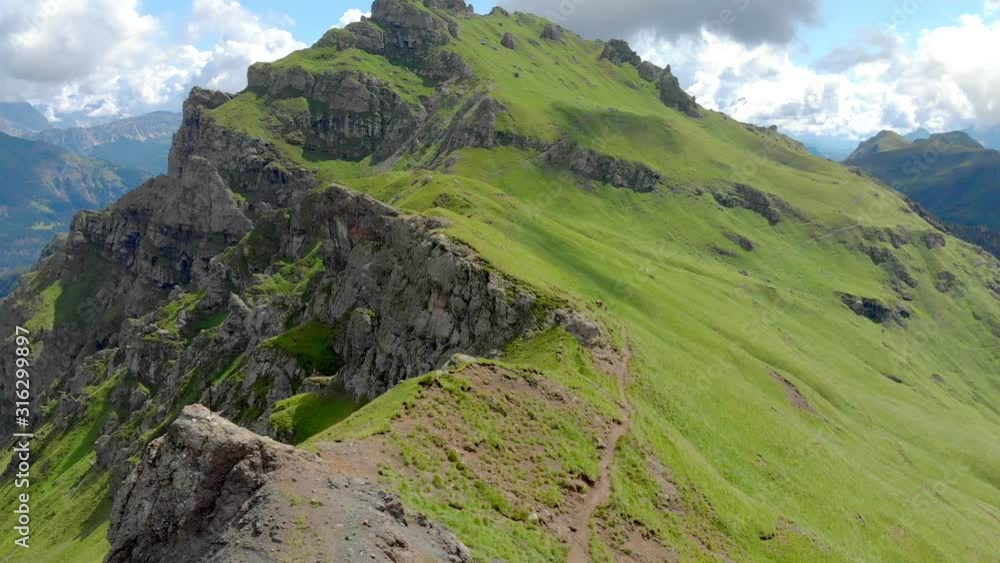 Mountain ridge, beautiful view of rocky cliff from one side and green grass on other side, small path with hikers, fly around aerial view, Dolomites, Italy 4k Mountain ridge, beautiful view of rocky cliff from one side and green grass on other side, small path with hikers, fly around aerial view, Dolomites, Italy 4k