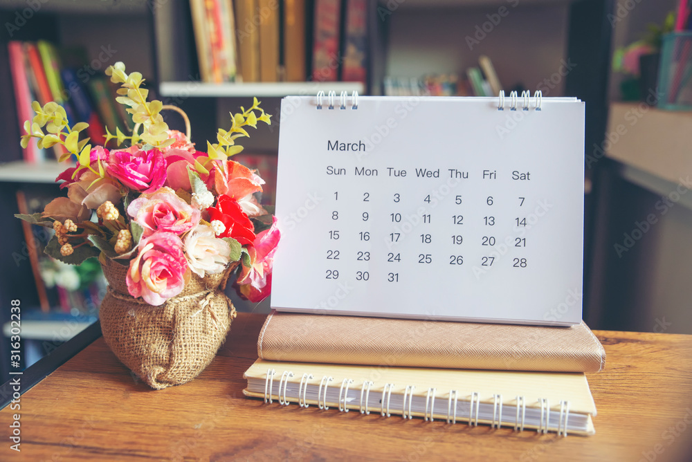 Planner and Calendar Concept.Desktop Calendar 2020,notebook and vase of rose flower placed on office desk in library.