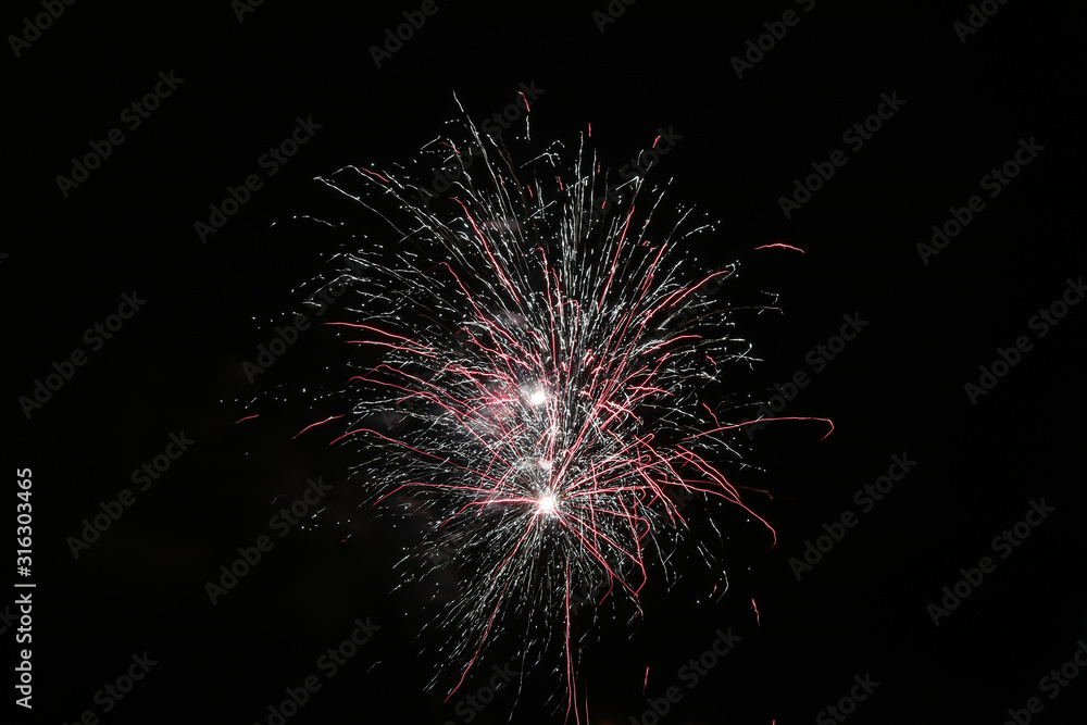 Festive fireworks against the black night sky. Light from the fi Festive fireworks against the black night sky. Light from the fi