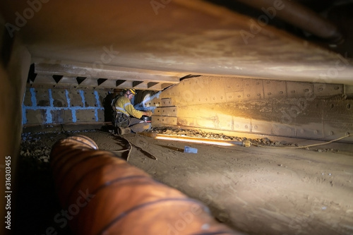 Construction worker wearing personal protective equipment working in confined spaces and using ventilation fan while air atmosphere is changing all the times 