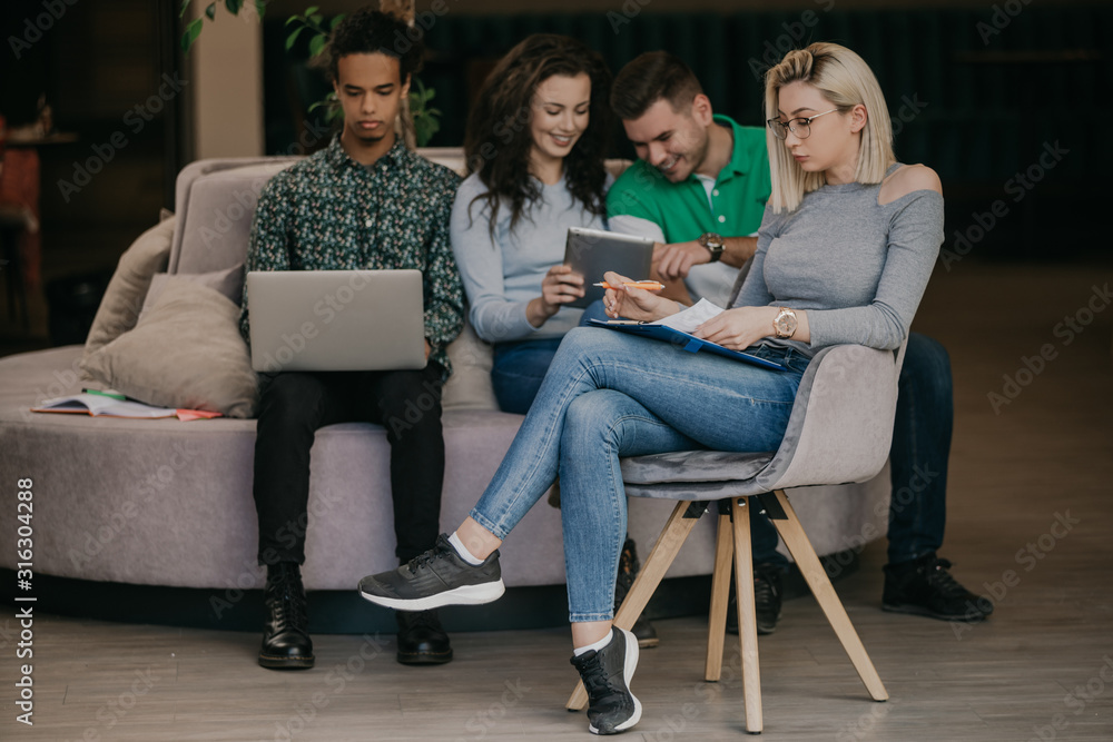 Diverse group of smiling young designer working together over a laptop during a meeting in the boardroom of a modern office Diverse group of smiling young designer working together over a laptop during a meeting in the boardroom of a modern office