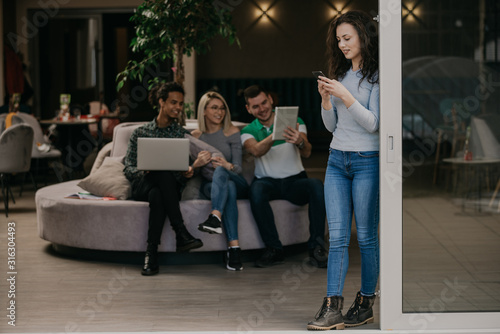 Woman on break, in background coworker team working on project