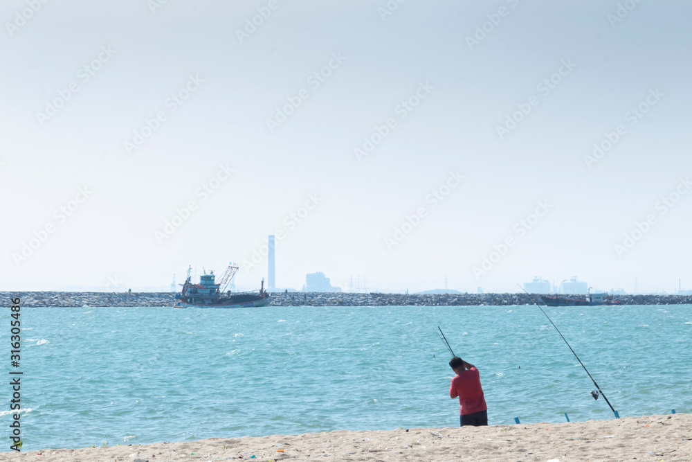 Men wearing red shirts were fishing with a hook. On the beach front, a fishing boat was returning to shore and people wearing fishing.