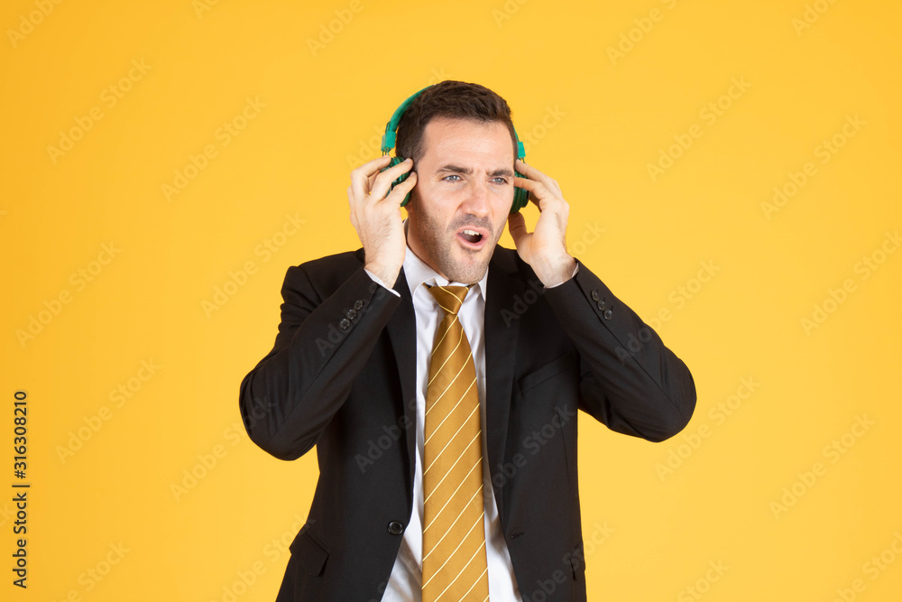 Portrait of confident businessman using headphone on yellow background. Portrait of confident businessman using headphone on yellow background.