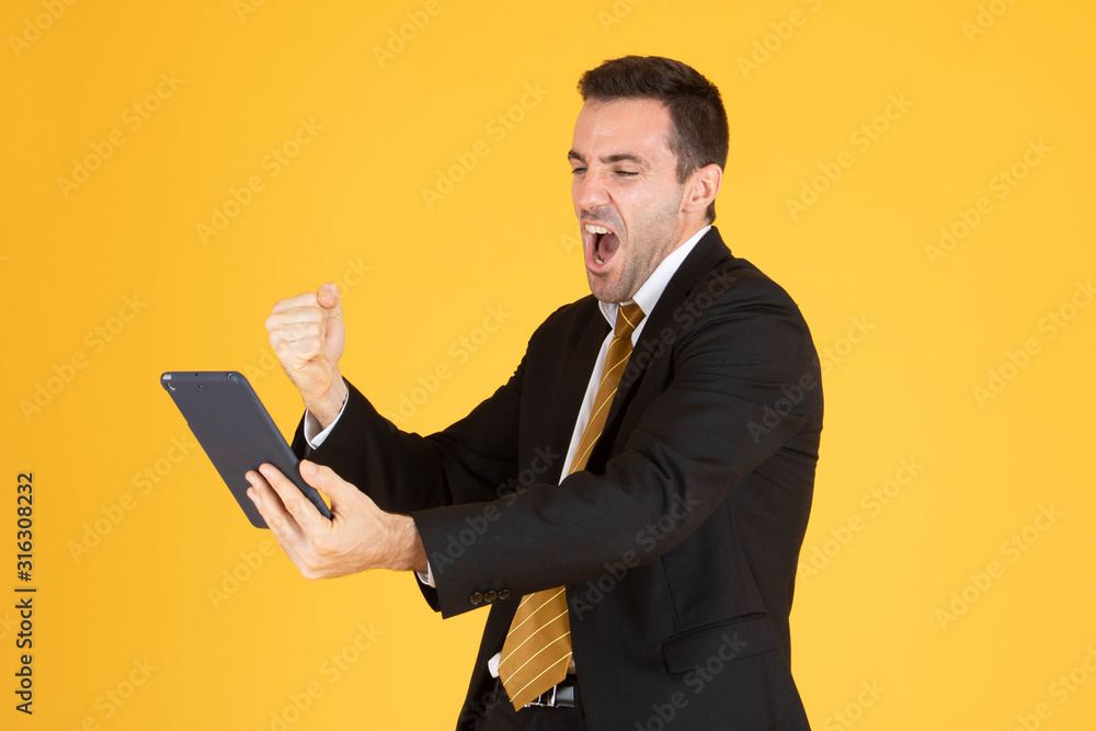 Portrait of cheerful businessman using tablet on yellow background. Portrait of cheerful businessman using tablet on yellow background.