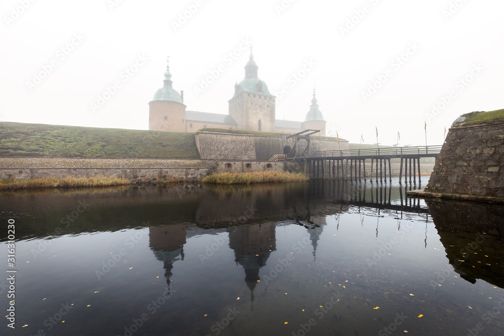 Bridge to Kalmar castle entrance an autumn day with heavy fog.