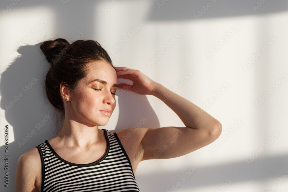 young pretty attractive brunette girl near a white wall with different emotions, hard light, light and shadow young pretty attractive brunette girl near a white wall with different emotions, hard light, light and shadow