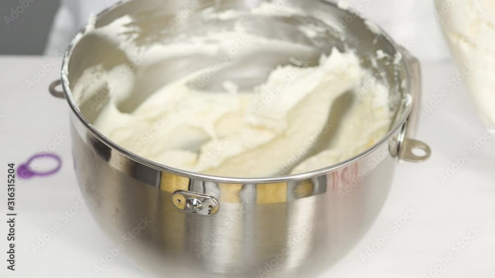 Step by step. Scooping a white buttercream frosting into a piping bag to decorate vanilla cupcakes. Step by step. Scooping a white buttercream frosting into a piping bag to decorate vanilla cupcakes.