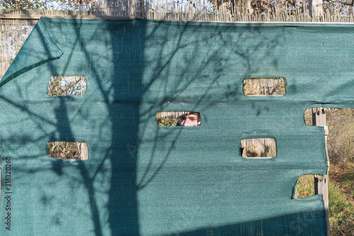 Man hidden behind a bird hide. Naturalistic route at the Oasis Brabbia marsh, province of Varese, Italy.  The marsh Brabbia is recognized as a wetland of international importance from 1984  photo