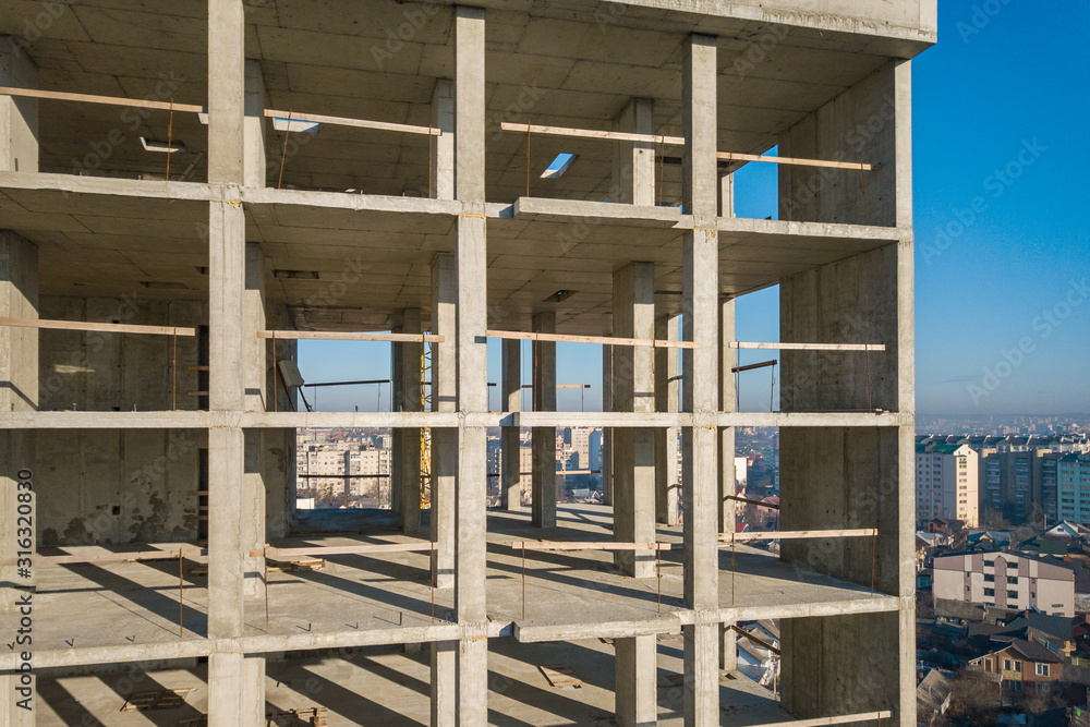 Obraz premium Aerial view of concrete frame of tall apartment building under construction in a city.
