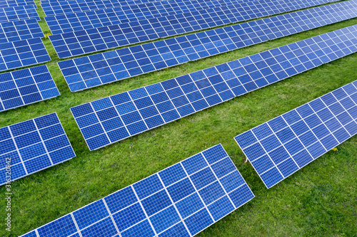 Surface of solar photo voltaic panels system producing renewable clean energy on green grass background.