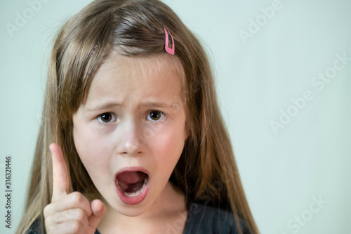 Close up portrait of angry shouting child girl looking aggressively in camera.