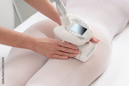 Woman in special white suit getting anti cellulite massage in a spa salon. LPG, and body contouring treatment in clinic. photo