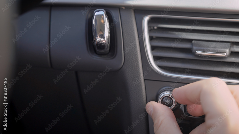 In the frame, a man s hand and a car audio volume knob. The driver or passenger adjusts the volume level of the music.