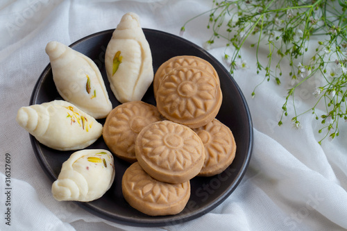 Shankh shaped sondesh and round sondesh kept in a bowl together.	