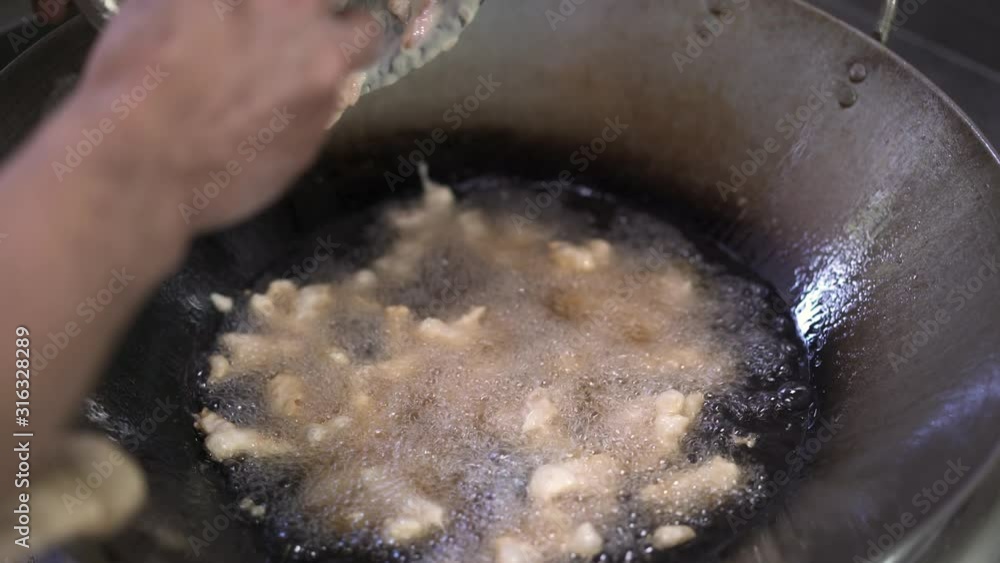Close up of putting small pieces of chicken in sauce on frying pan. Handheld shot of cook putting slices of chicken into boiling oil in frying pan in chinese kitchen restaurant Close up of putting small pieces of chicken in sauce on frying pan. Handheld shot of cook putting slices of chicken into boiling oil in frying pan in chinese kitchen restaurant