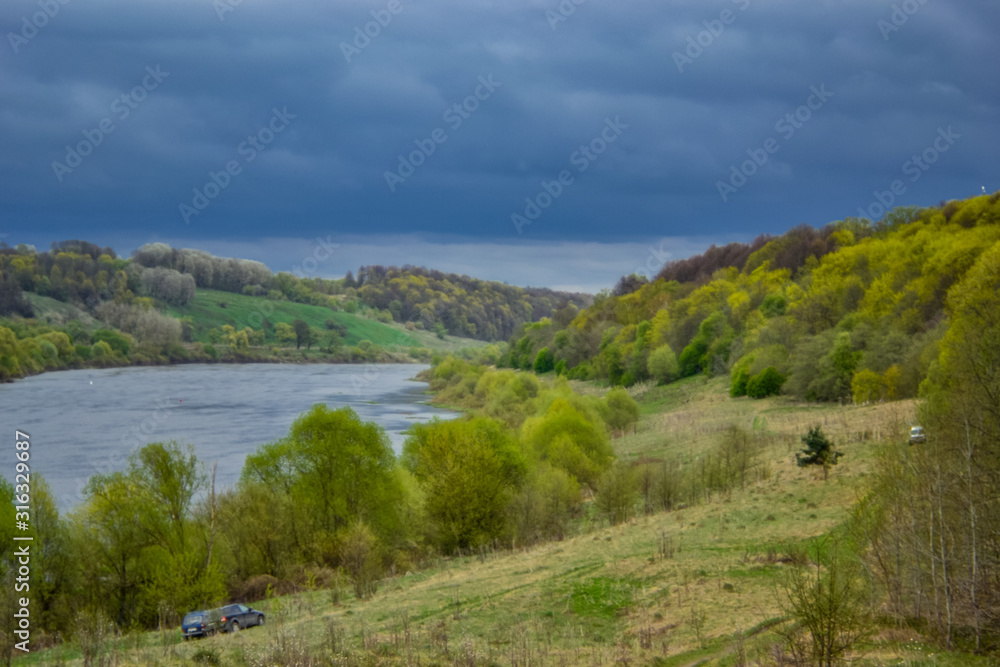 The rural nature river dark sky landscape. The nature of the river. Rural river landscape. There are several cars on the river bank