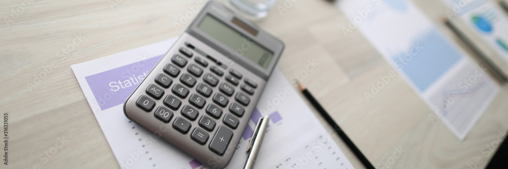 Focus on light wooden table in meeting room. Water bottles with glasses, paper sheets with statistics documents, pen, pencil and calculator on desk. Business negotiations concept. Blurred background Focus on light wooden table in meeting room. Water bottles with glasses, paper sheets with statistics documents, pen, pencil and calculator on desk. Business negotiations concept. Blurred background